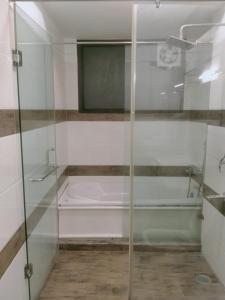 新德里Green Lotus La Wisteria Inn的浴室设有玻璃淋浴间和浴缸