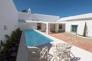 科尼尔-德拉弗龙特拉CORTIJO LA MINA - Luxury Villa Conil的白色的房子,设有游泳池和椅子