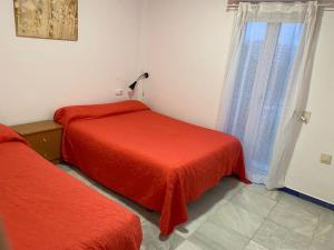 圣玛丽亚港Apartamento Medina Puerto Sherry的一间卧室设有两张带红色床单的床和窗户。