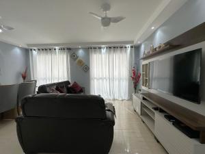 瓜鲁雅Pé na Areia a Poucos Metros -Apartamento Guarujá Pitangueiras的客厅配有平面电视和沙发。