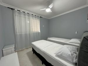 瓜鲁雅Pé na Areia a Poucos Metros -Apartamento Guarujá Pitangueiras的一间卧室配有两张床和吊扇
