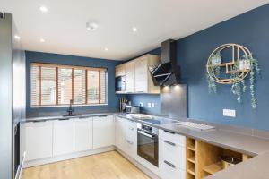 布莱顿霍夫Stylish & modern 4-bedroom home with sea views的厨房配有白色橱柜和蓝色的墙壁