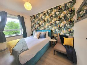 阿伯丁Business & Familes Three Bedrooms By Sensational Stay Short Lets & Serviced Accommodation, Aberdeen With Balcony & Free Parking的一间卧室配有一张床和一张带壁纸的椅子