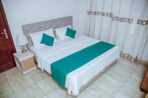 基加利Room in BB - Martin Aviator Hotel的卧室配有带绿色枕头的大型白色床