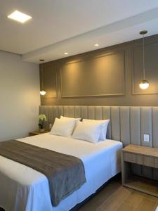 卡皮托利乌Vista do Lago Hotel的卧室配有带白色枕头的大床