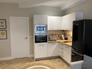 莱昂Apartamento Cielo del Norte VUT LE-933的厨房配有白色橱柜和黑色冰箱。