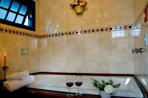 维奥康德马奥Hotel Bühler的一间带浴缸及两杯葡萄酒的浴室