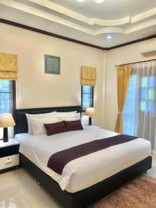 邦涛海滩Malinee Villa Phuket的一间卧室设有一张大床和两个窗户。