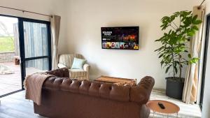纳库鲁The Croft的客厅配有棕色真皮沙发和平面电视。