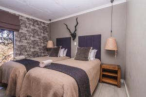 帕雷斯Thabela Thabeng的一间卧室设有两张床和砖墙