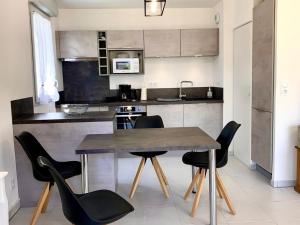 迈兹Appartement Mèze, 3 pièces, 4 personnes - FR-1-604-27的厨房配有木桌和黑色椅子