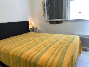 迈兹Appartement Mèze, 3 pièces, 4 personnes - FR-1-604-27的一间卧室配有一张黄色和绿色毯子的床