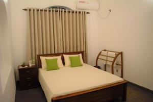 卡图纳耶克Murphy's Villa的一间卧室配有一张带绿色枕头的床和一扇窗户