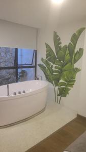 马尼萨莱斯Hotel Piedras De Maní的带浴缸旁的大植物的浴室