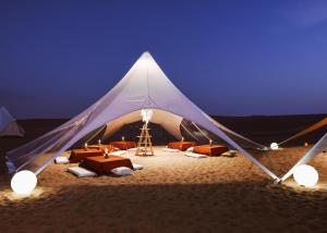 伊察Duna Camp Huacachina的海滩上的一个帐篷,晚上配有桌椅
