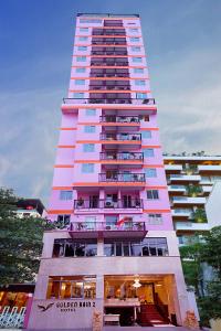 芽庄金雨2号酒店的一座高大的粉红色建筑,设有阳台
