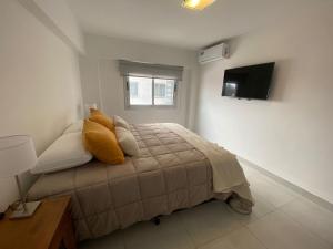 萨尔塔HAUS APARTAMENTOS的一间卧室配有一张带黄色枕头的床和电视。