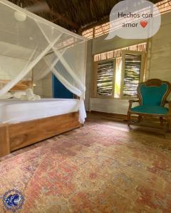 MoñitosPlaya Jaguar - Beach Club的一间卧室配有天蓬床和蓝椅