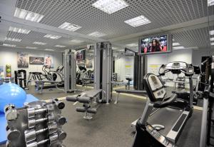 伦敦伦敦帕丁顿美居酒店的健身房设有有氧器材和平面电视