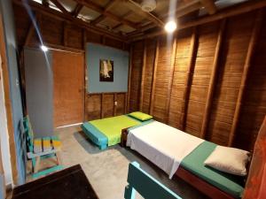 塔甘加Casa MITA Taganga的一间带两张床铺的卧室,位于带木墙的房间内
