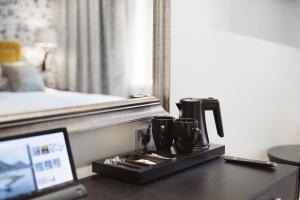 赫尔辛基Hotel Bastian的酒店客房的办公桌上配有咖啡壶和笔记本电脑