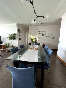 伊基克apartamento con vista al mar y piscina.的一间设有玻璃桌和蓝色椅子的用餐室