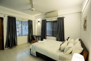 达卡Gulshan Lovely 3-Bedroom Luxury Apartment的卧室配有白色的床和黑色窗帘