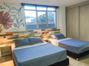 麦德林Neim Platinum Hotel的一间卧室设有两张床和花卉壁画