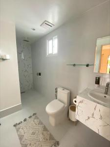 莫阿尔博阿HARMAN SUITES Moalboal的白色的浴室设有卫生间和水槽。