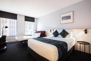墨尔本CitiClub Hotel Melbourne的酒店客房设有一张大床和一张书桌。