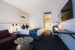 墨尔本CitiClub Hotel Melbourne的酒店客房,配有床和沙发