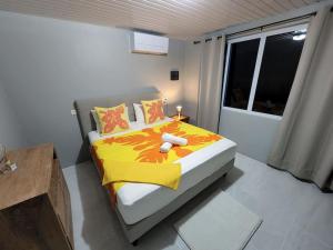 MaateaMaddy's House的一间卧室配有一张带黄色毯子和窗户的床