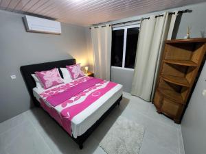 MaateaMaddy's House的一间卧室配有一张带粉色床单的床和一扇窗户。
