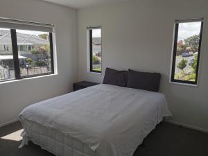 奥克兰Stunning Stay In Papatoetoe Auckland的一间卧室设有一张大床和两个窗户