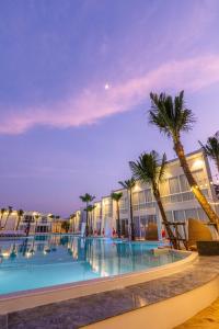 农布The Gems Mining Pool Villas Pattaya的棕榈树和建筑的夜间游泳池