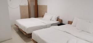阿罗士打Tang Hotel的配有白色床单的客房内的两张床