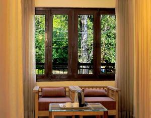 兰纳加Hotel Holiday Highlights的一间设有两张长椅和一张桌子及窗户的房间
