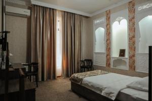 布哈拉奥马尔希亚姆酒店的配有一张床和一张书桌的酒店客房