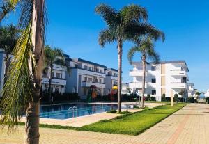 曼苏里亚Marbella Beach location pour famille 2 chambres的一座楼前棕榈树游泳池