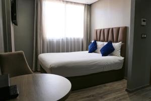 卡萨布兰卡勒22公寓式酒店的一间卧室配有一张带蓝色枕头的床和一扇窗户。