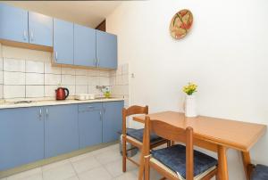 拉巴克Apartments Plominska 938的厨房配有蓝色橱柜和木桌