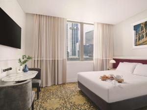 墨尔本墨尔本汇合酒店的配有一张床、一张书桌和一扇窗户的酒店客房