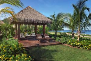 PortsmouthInterContinental Dominica Cabrits Resort & Spa, an IHG Hotel的一个带椅子的木制甲板和凉亭