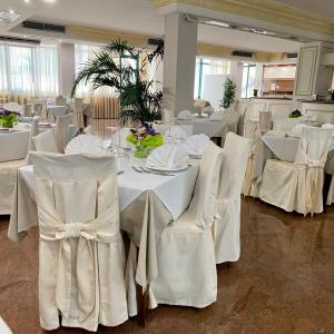 切萨雷奥港Porto Cesareo Hotel的用餐室配有白色的桌子和白色的椅子