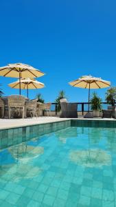 福塔莱萨Carppa Hotel的一个带椅子和遮阳伞的游泳池
