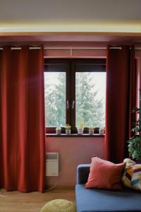 兹拉蒂博尔Apartman Dream的客厅配有红色窗帘和蓝色沙发