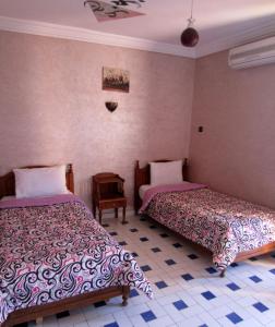 马拉喀什Marrakech Hôtel Résidence的一间卧室配有两张床和一张桌子
