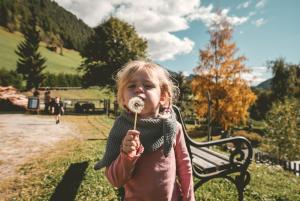 普雷格拉滕Familienhotel Replerhof mit Kinderbetreuung的一个小女孩在棍子上吃甜甜圈