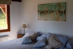 拉安戈斯图拉镇Casa del Sur Villa La Angostura的卧室配有一张床,墙上挂有绘画作品