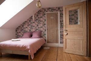 蒙贝利亚尔Le Parc du Magnolia的一间卧室配有一张带粉红色床单的床,铺有木地板。